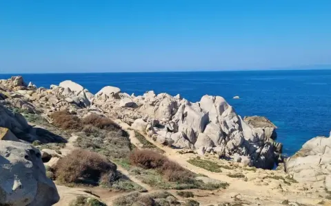 Felsige Küste am Capo Testa, Sardinien, mit tiefblauem Meer und klarem Himmel.