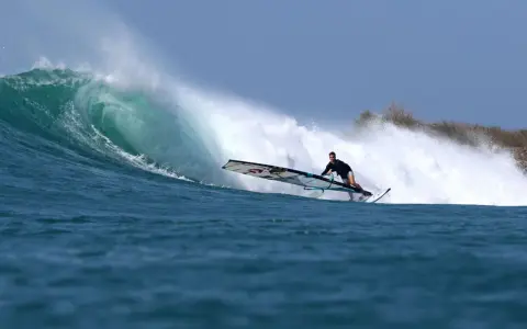 Liam Dunkerbeck surft eine massive Welle, die Gischt spritzt.