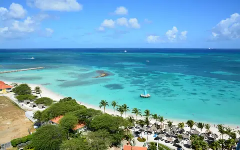 Traumhafter Strand mit Palmen und türkisfarbenem Wasser. Ein Ort wie Aruba oder Curacao, perfekt für einen Urlaub.