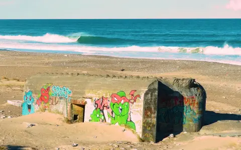 Bunker mit Graffiti am Strand von Klitmoller, Dänemark. Wellen brechen im Meer.