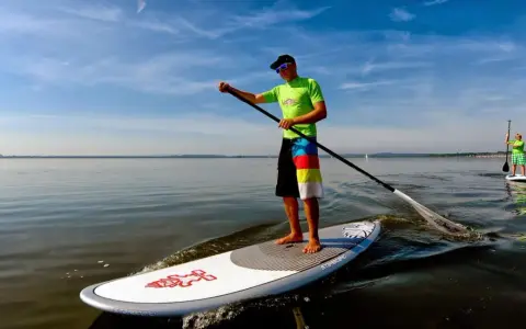 Ein Mann genießt das Steinhuder Meer beim SUP. Im Hintergrund paddelt eine weitere Person.
