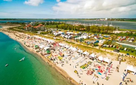 Strandfest mit vielen Zelten und Ausrüstung für Windsurfing Wulfen. Menschen genießen das sonnige Wetter am Meer.
