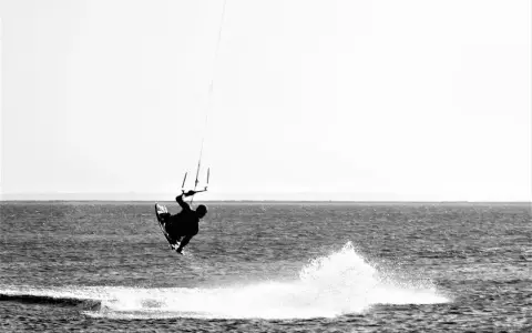 Kitesurfer in der Luft vor Fehmarn. Ein Sprung über das Wasser, der die Freiheit des Windsurfens zeigt.