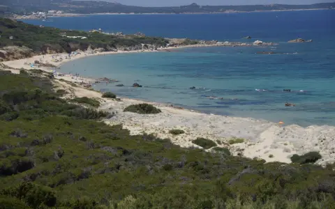 Ein sonniger Tag am Vignola Mare. Türkisfarbenes Meer, Sandstrand mit wenigen Menschen und üppige grüne Vegetation.