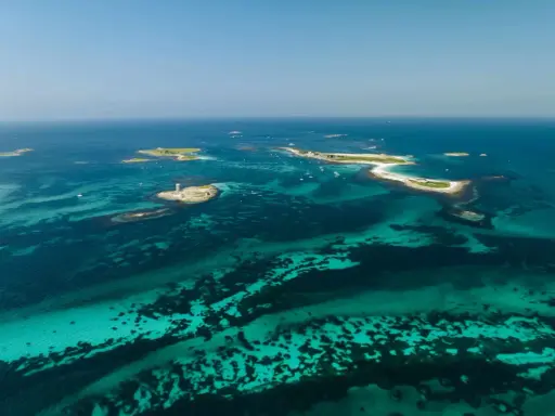 Türkisblaues Wasser umgibt die Glenan Inseln mit einem Leuchtturm auf einer kleinen Insel.