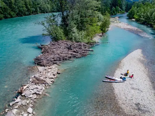 Standup paddling am Feldmarksee: Zwei Personen ruhen sich auf einer Kiesbank aus, während zwei Boards im türkisfarbenen Wasser liegen.