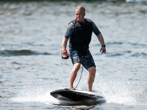Mann fährt mit einem Surfbrett mit Motor über das Wasser.