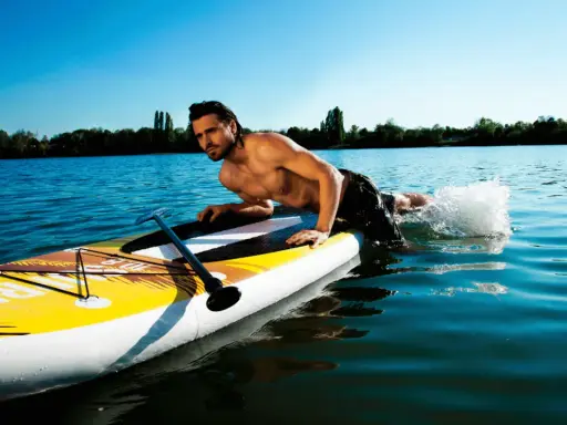 Mann liegt auf SUP-Board, paddelt mit Armen im Wasser. Perfekt für eine SUP Tour auf dem See.