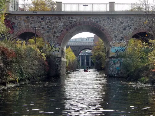 Kanus auf dem Fluss unter einer Steinbrücke mit Graffiti. Sup Leipzig!