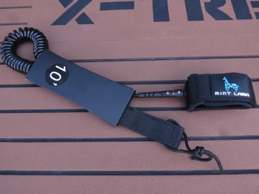 Schwarze SUP Leash mit 10' Kennzeichnung und Mint Lama Logo, bereit zur Befestigung.