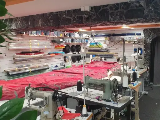 Werkstatt für wing reparatur mit Nähmaschinen und Stoffrollen.