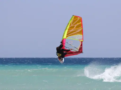 Windsurfer springt hoch über türkisfarbener Welle vor Teneriffa. Ein spektakulärer Sprung beim Teneriffa Windsurfen.
