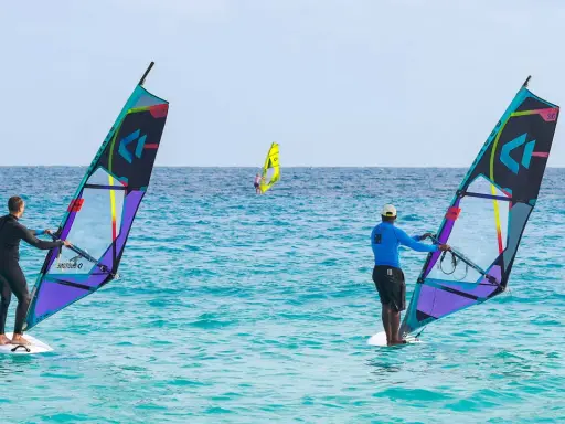 Windsurfer auf dem Meer vor Santa Maria Sal. Zwei Surfer mit bunten Segeln genießen den Tag auf dem türkisfarbenen Wasser.