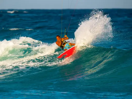 Brian Talma surft auf einer Welle, während er mit einem Kiteboard durch die Gischt fährt.