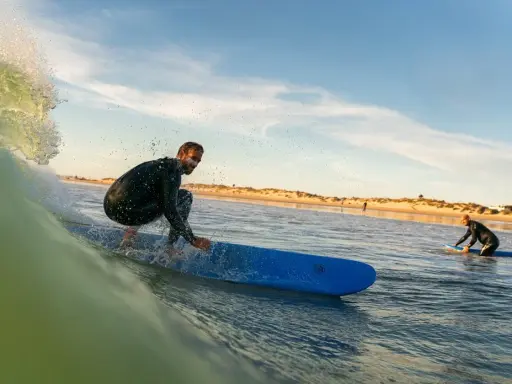 Surfer reitet eine Welle vor der Küste von Tarifa. Ein weiterer Surfer wartet im Wasser.
