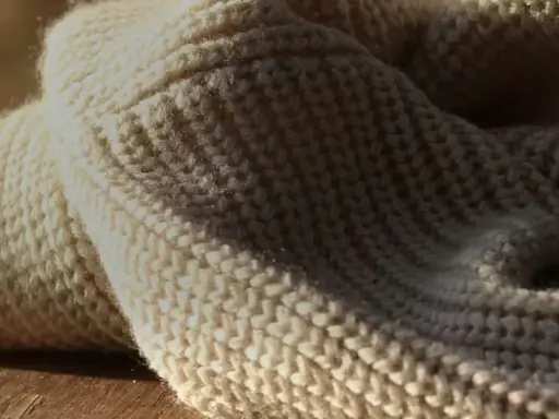 Weiches, cremefarbenes Strickgewebe, das an die Herkunft von Merinowolle erinnert.