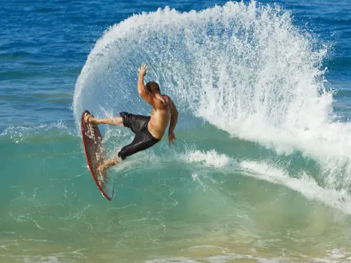 Mann surft ohne segel auf einer welle, die Gischt spritzt. Ein aufregender Moment des Wassersports.