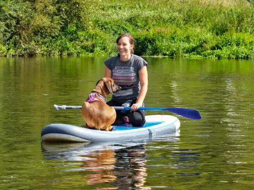 Frau und ihr sup hund krallen auf dem Fluss.