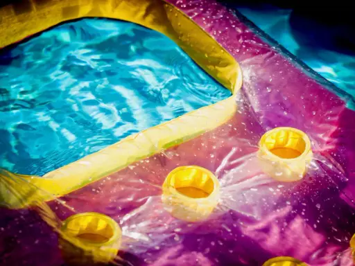 Bunte Luftmatratze mit Becherhaltern im Wasser, bereit zum Luftmatratze flicken.