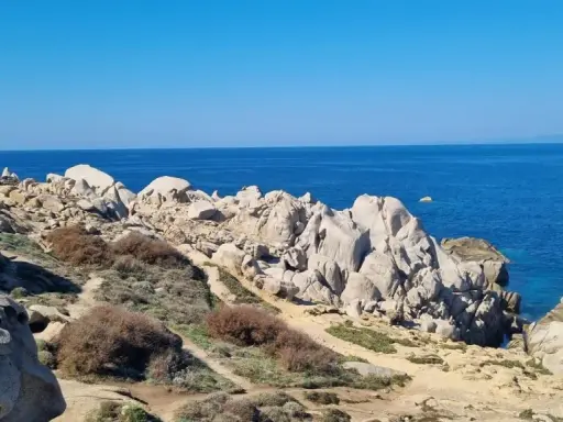 Felsige Küste am Capo Testa, Sardinien, mit tiefblauem Meer und klarem Himmel.