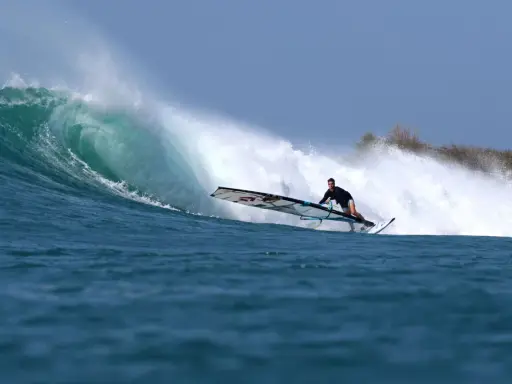 Liam Dunkerbeck surft eine massive Welle, die Gischt spritzt.