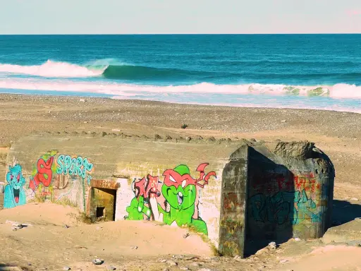 Bunker mit Graffiti am Strand von Klitmoller, Dänemark. Wellen brechen im Meer.
