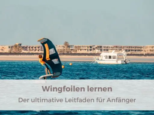 Person lernt wingfoilen auf dem Meer, mit einem Boot und Gebäuden im Hintergrund. Der ultimative Leitfaden für Anfänger.