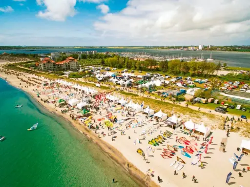 Strandfest mit vielen Zelten und Ausrüstung für Windsurfing Wulfen. Menschen genießen das sonnige Wetter am Meer.