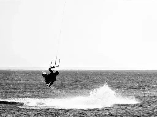 Kitesurfer in der Luft vor Fehmarn. Ein Sprung über das Wasser, der die Freiheit des Windsurfens zeigt.