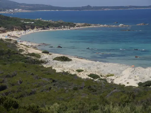 Ein sonniger Tag am Vignola Mare. Türkisfarbenes Meer, Sandstrand mit wenigen Menschen und üppige grüne Vegetation.