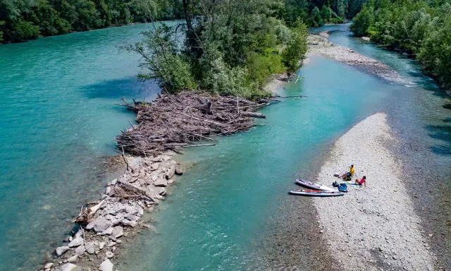 Standup paddling am Feldmarksee: Zwei Personen ruhen sich auf einer Kiesbank aus, während zwei Boards im türkisfarbenen Wasser liegen.