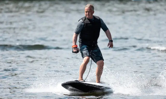 Mann fährt mit einem Surfbrett mit Motor über das Wasser.