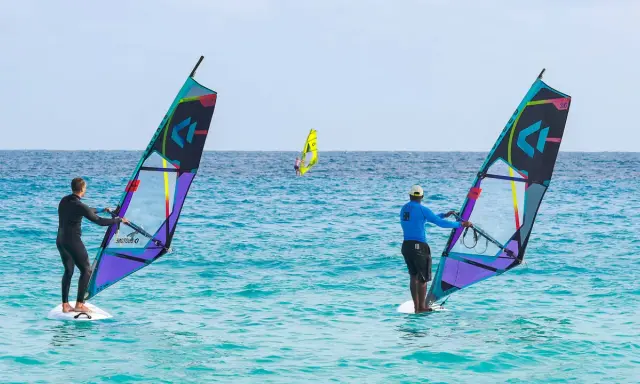 Windsurfer auf dem Meer vor Santa Maria Sal. Zwei Surfer mit bunten Segeln genießen den Tag auf dem türkisfarbenen Wasser.