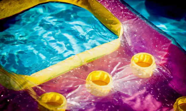 Bunte Luftmatratze mit Becherhaltern im Wasser, bereit zum Luftmatratze flicken.