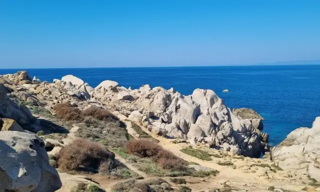 Felsige Küste am Capo Testa, Sardinien, mit tiefblauem Meer und klarem Himmel.