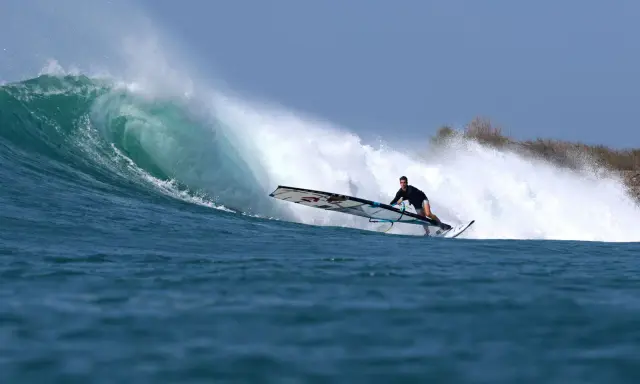 Liam Dunkerbeck surft eine massive Welle, die Gischt spritzt.