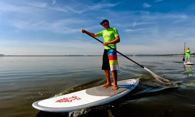 Ein Mann genießt das Steinhuder Meer beim SUP. Im Hintergrund paddelt eine weitere Person.