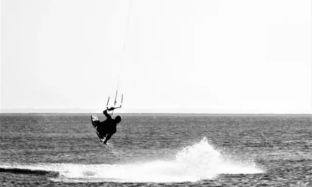 Kitesurfer in der Luft vor Fehmarn. Ein Sprung über das Wasser, der die Freiheit des Windsurfens zeigt.