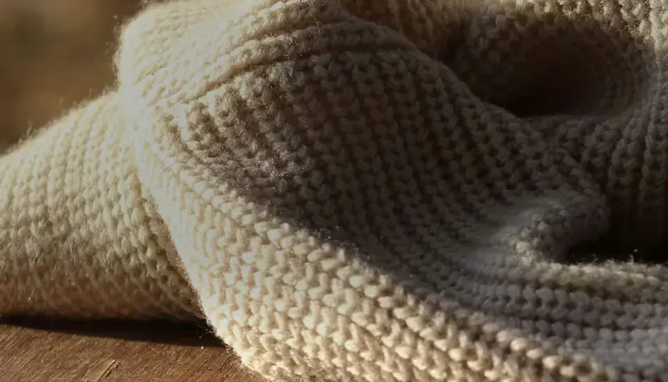 Weiches, cremefarbenes Strickgewebe, das an die Herkunft von Merinowolle erinnert.