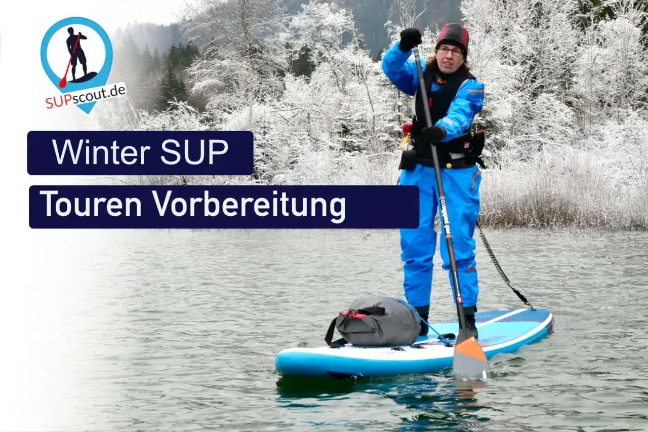 Person im blauen Neoprenanzug auf einem SUP-Board im Winter, bereit für Touren.