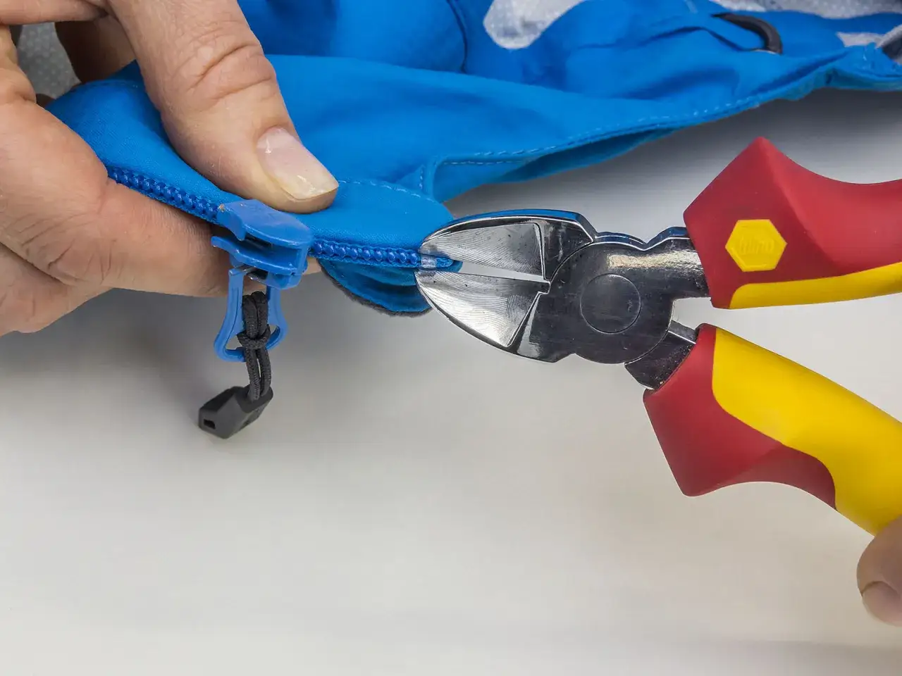 Mit einer Zange wird ein alter Rei&szlig;verschluss-Zipper ausgetauscht.