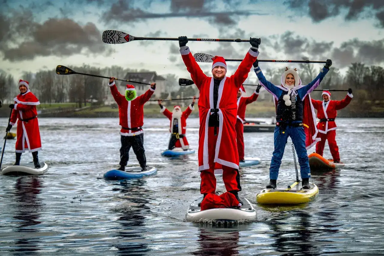 Weihnachtsmänner und ein Grinch auf SUP-Boards auf dem Rhein.