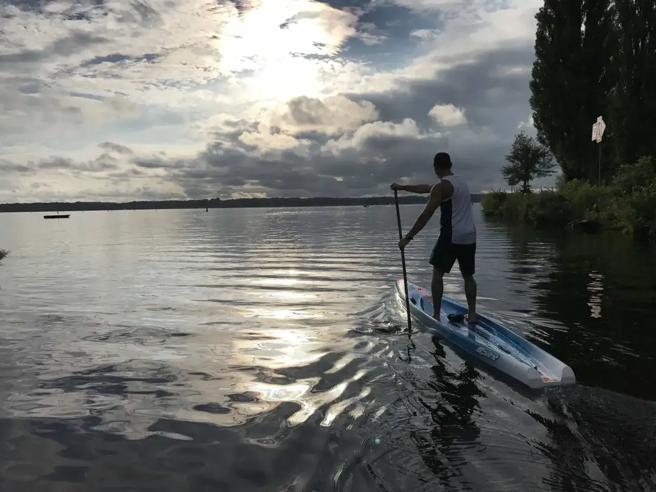 Mann auf SUP-Board in Potsdam, genießt den Sonnenuntergang über dem Wasser. Ein perfekter SUP Trip!