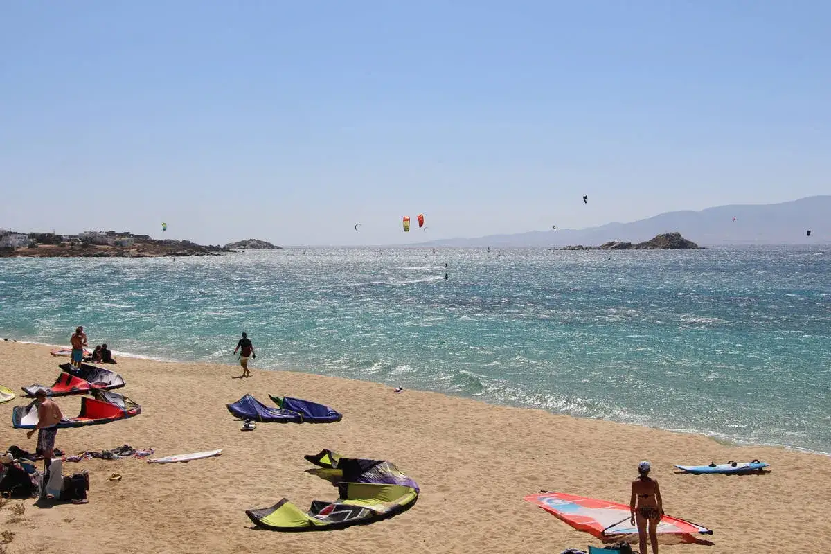 Windige Bedingungen am Strand von Naxos, ideal zum Surfen und Kitesurfen. Bunte Kites und Boards liegen am Sand.