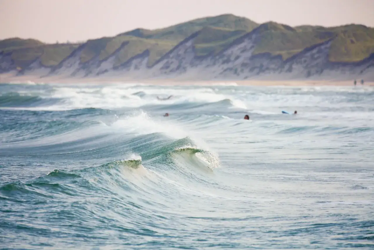 Wellen brechen sich am Strand von Klitmoller, D&auml;nemark. Surfer warten auf die n&auml;chste Welle.