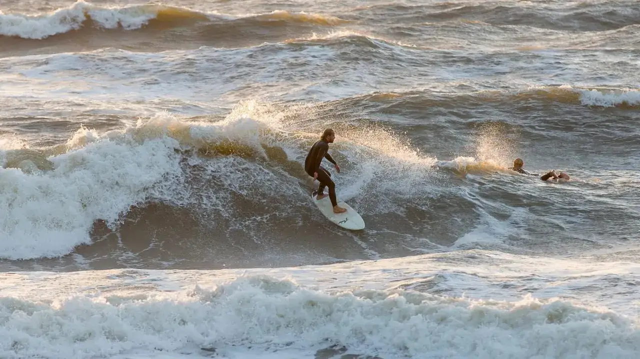 Surfer reitet Welle im Meer, ein weiterer wartet. Perfektes Surfen Holland!