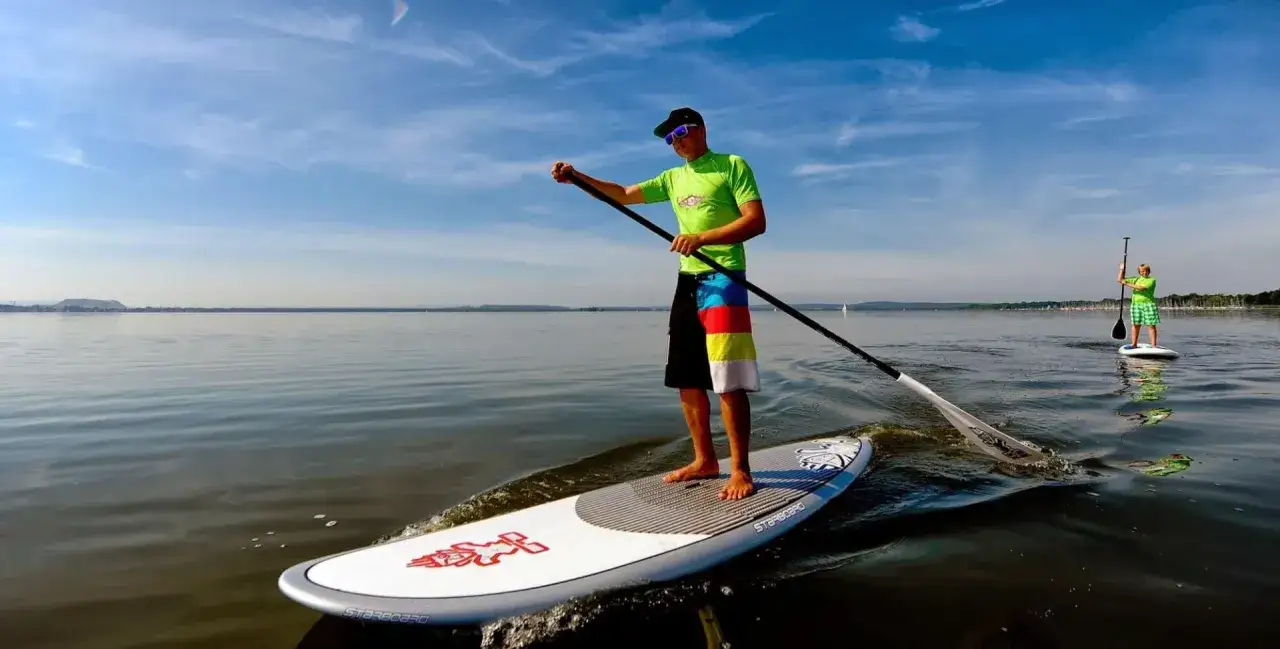 Ein Mann genießt das Steinhuder Meer beim Stand-Up-Paddling. Ein weiterer Paddler ist in der Ferne zu sehen.