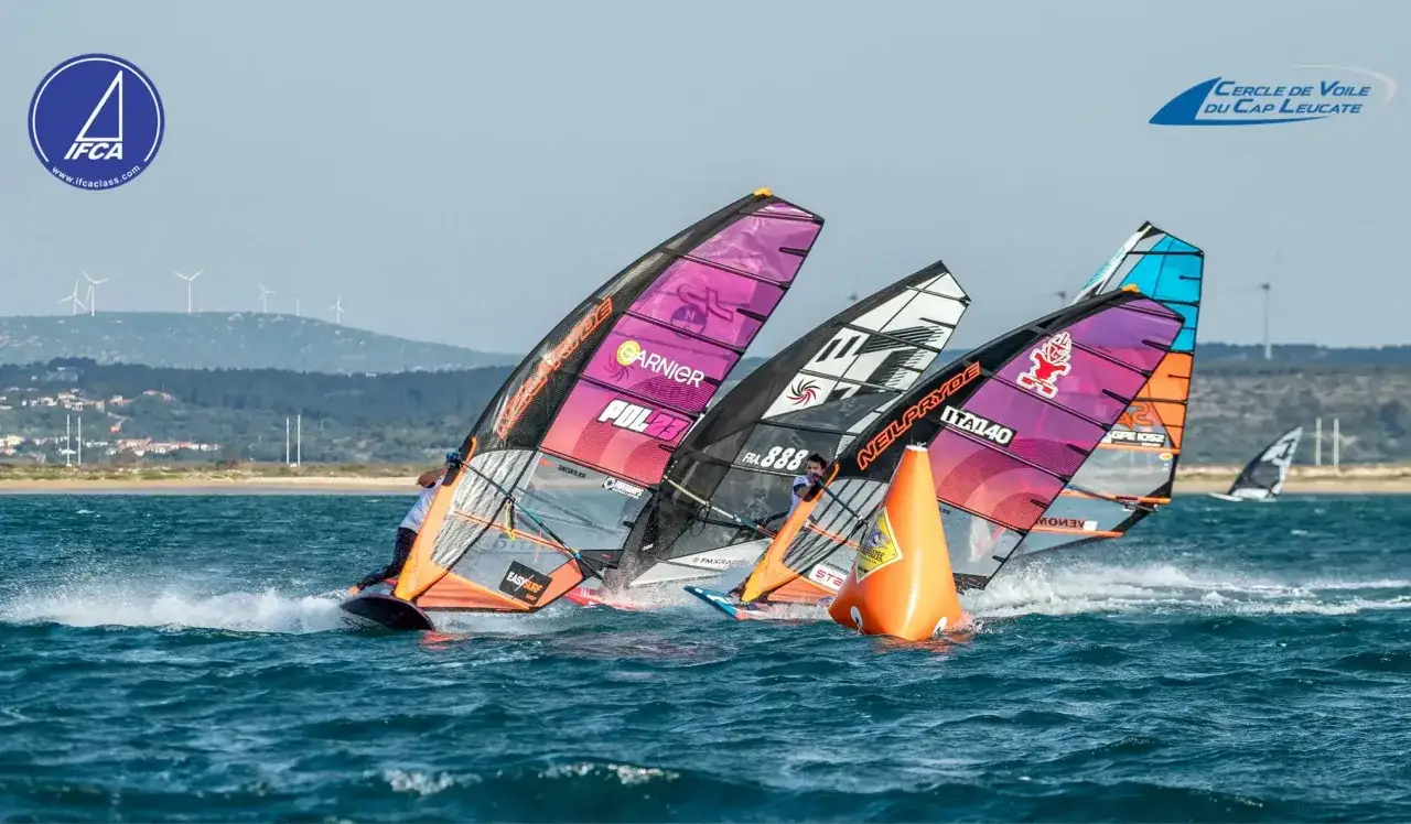 Windsurfer Maciej Rutkowski k&auml;mpft sich durch die Wellen, seine Segel in leuchtenden Farben.