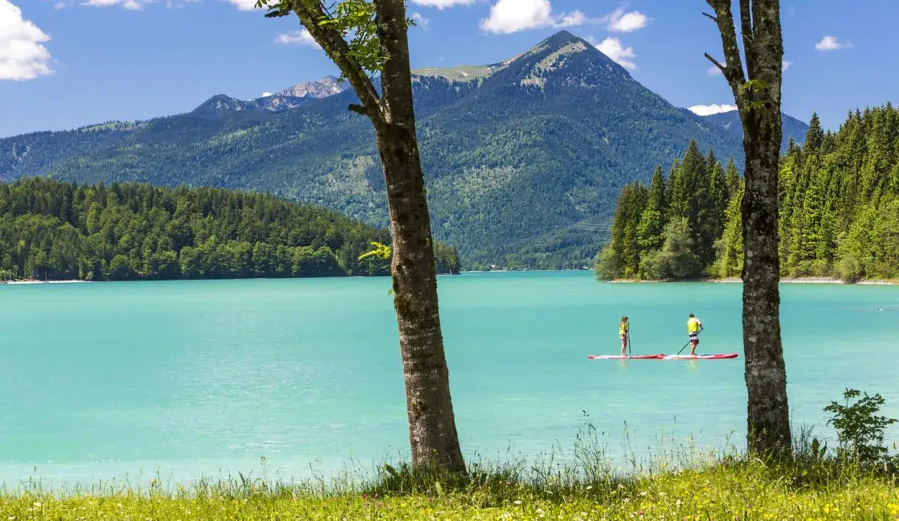 Sup Bayern! Zwei Paddler genießen die türkisblaue Bergkulisse auf dem See.
