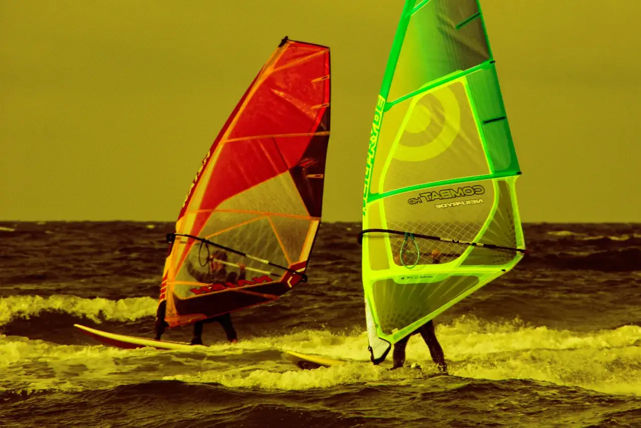 Zwei Windsurfer mit roten und gr&uuml;nen Segeln auf dem Meer. Ein aufregender Tag f&uuml;r Surf und Segel Hiddensee.